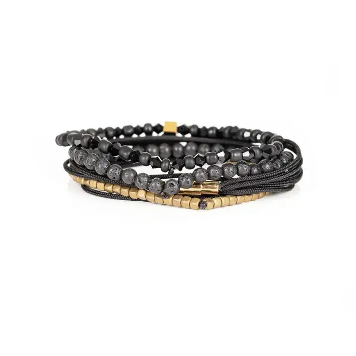 Black and gold layered men’s bracelet set with lava stone beads, gold cube accents, faceted black beads, braided rope wraps, and metallic centerpiece on white background.