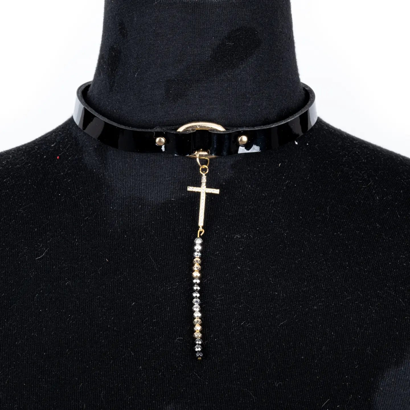 Black leather choker with a gold cross pendant and a long beaded chain drop, displayed on a white background.