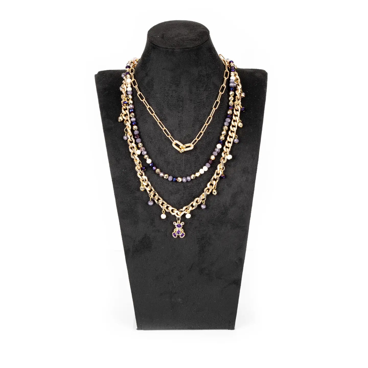 Layered gold necklace with purple crystal beads and small bear charm on white background.