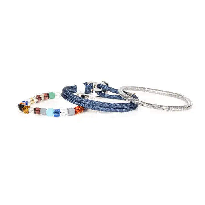 Men’s layered bracelet set featuring blue braided cord, silver-tone coil wrap, faceted crystal cube beads in blue, orange, gray, black, and clear tones, finished with polished metal accents in a modern luxury style on a white background.
