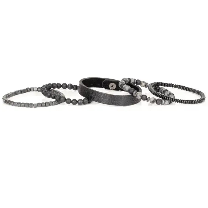 Men’s layered bracelet set featuring a black textured leather cuff, matte black lava stone beads, gray marbled stone beads, hematite cube beads, and black heishi spacers, stacked in a rugged contemporary luxury design on a white background.