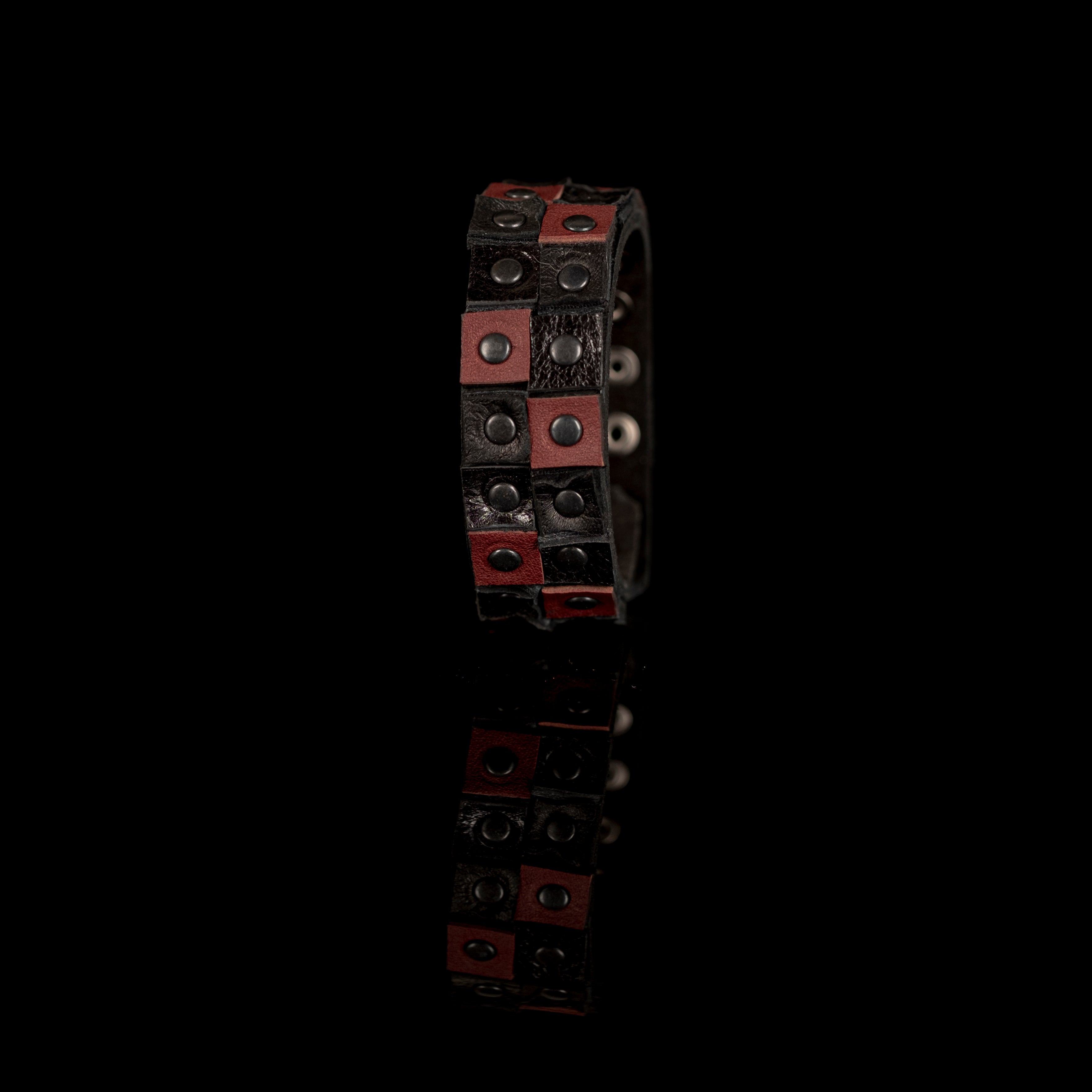 Men's black and brown leather cuff bracelet featuring a double-row studded design with gunmetal rivets and handcrafted leather panels.