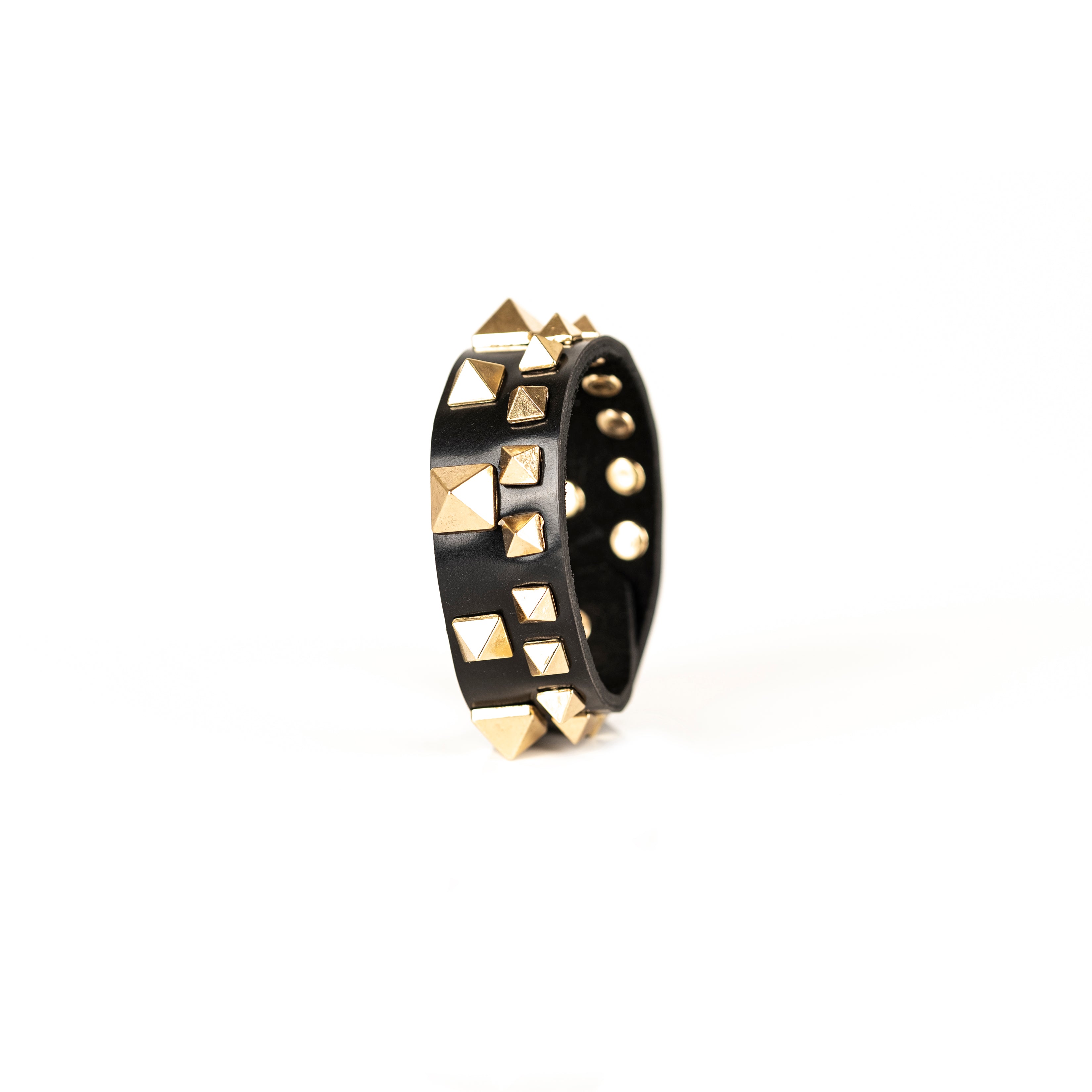 Black leather cuff bracelet with gold pyramid studs and geometric metal details, handmade statement bracelet by THE DARK