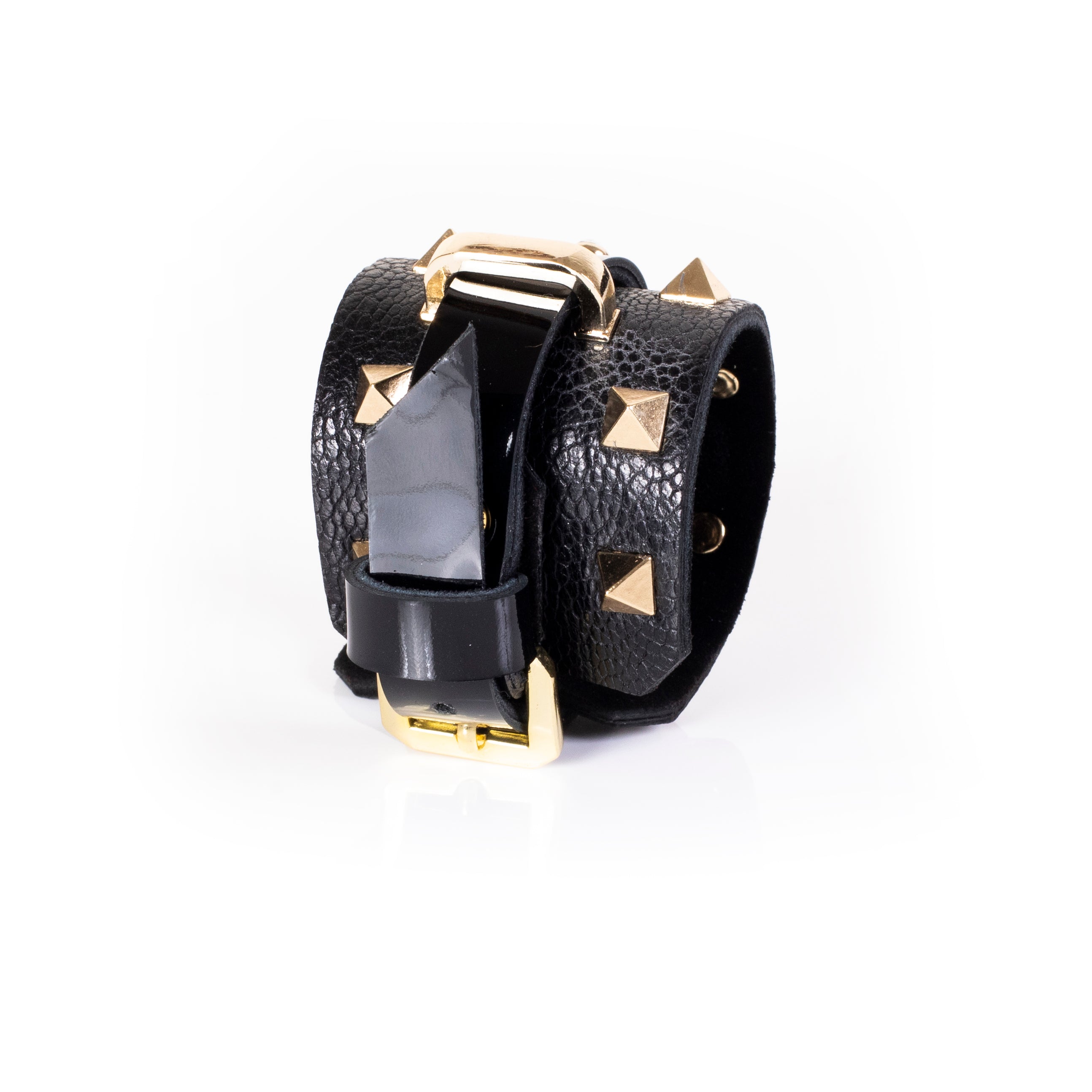 Black leather wrap cuff bracelet with gold pyramid studs, central glossy strip, crystal accent and gold buckle detail, handcrafted statement bracelet for women by THE DARK
