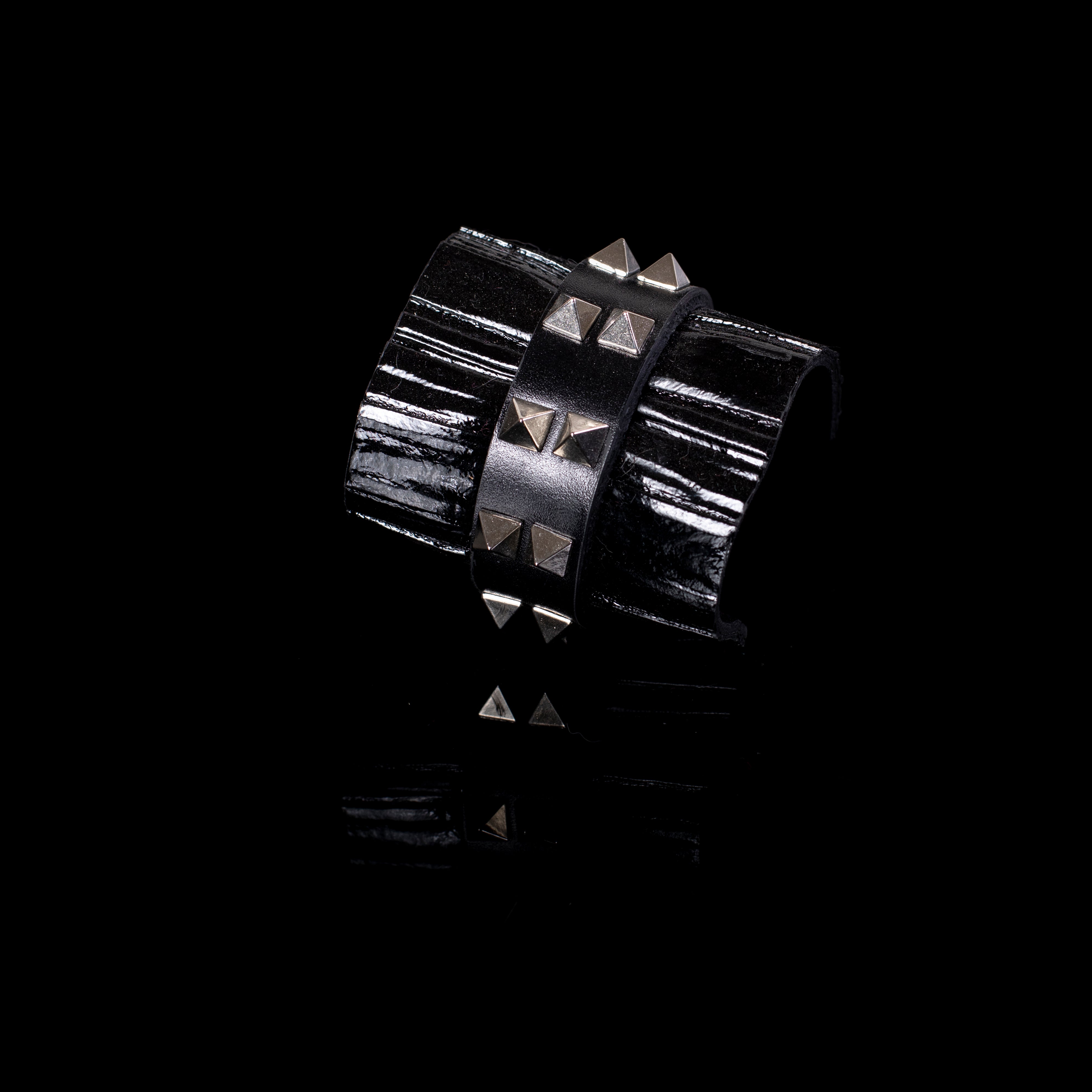 Black patent leather cuff bracelet with central studded leather band and glossy textured surface, wide handcrafted statement bracelet for women by THE DARK