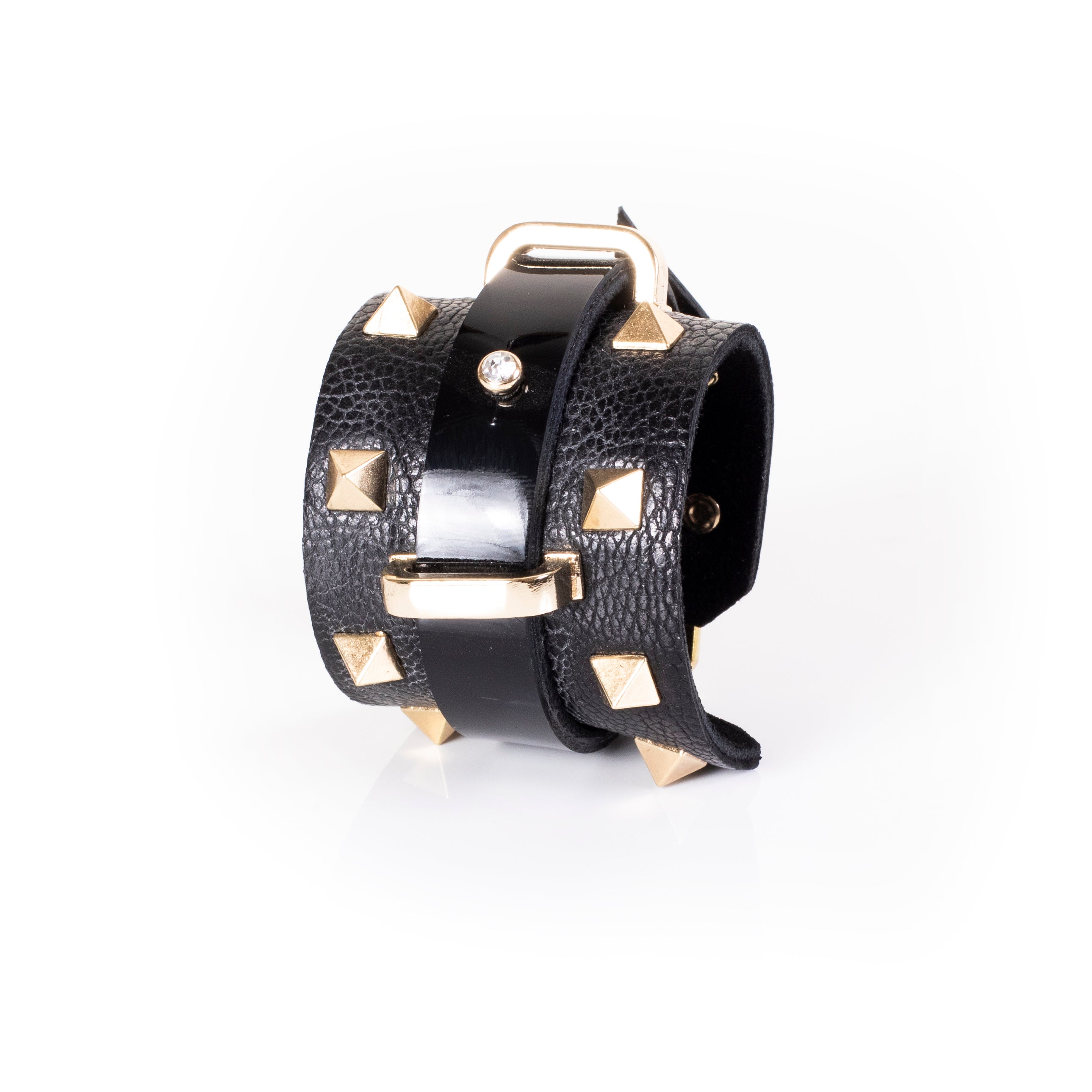 Black leather wrap cuff bracelet with gold pyramid studs, central glossy strip, crystal accent and gold buckle detail, handcrafted statement bracelet for women by THE DARK