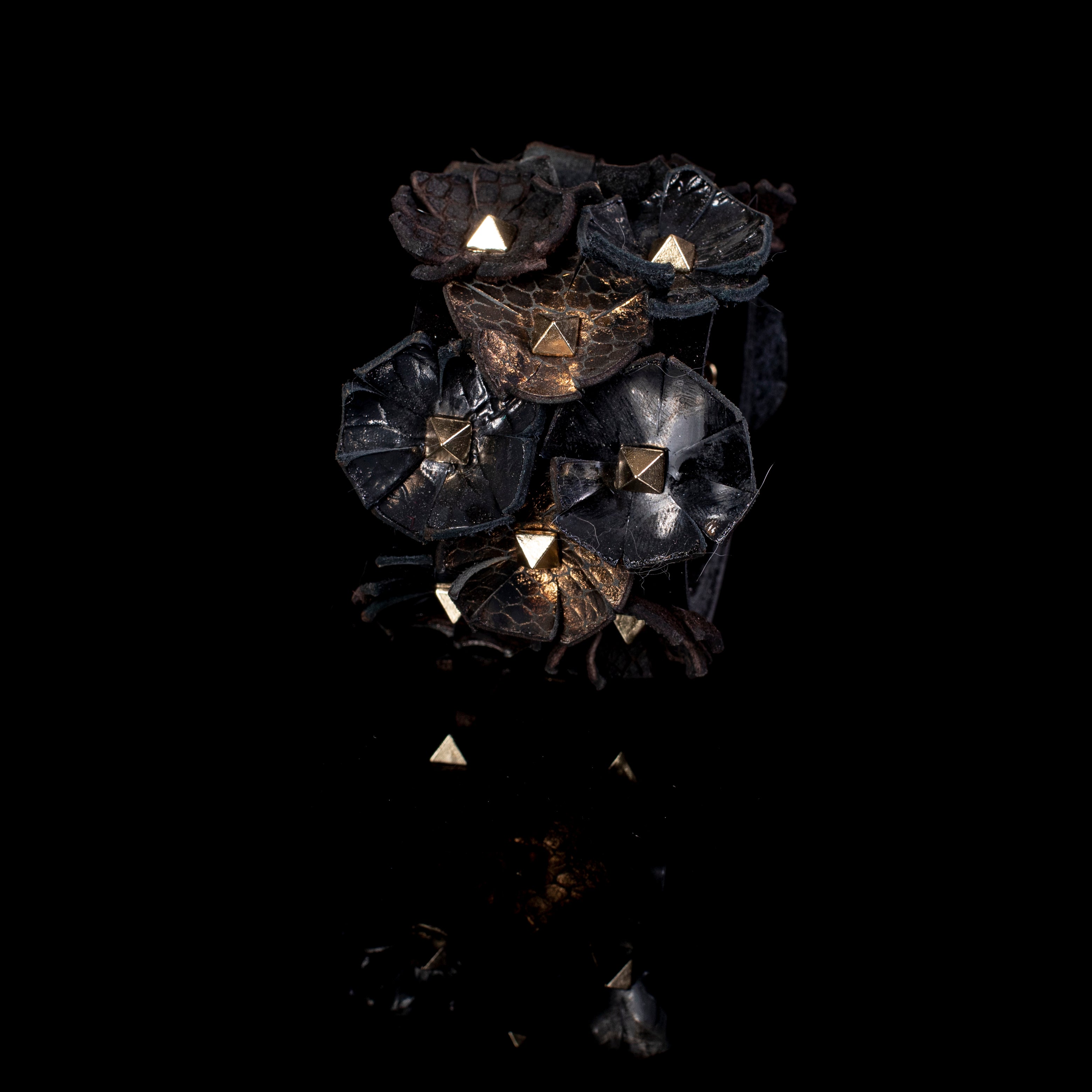 Black leather cuff with multiple sculpted floral elements and gold pyramid studs