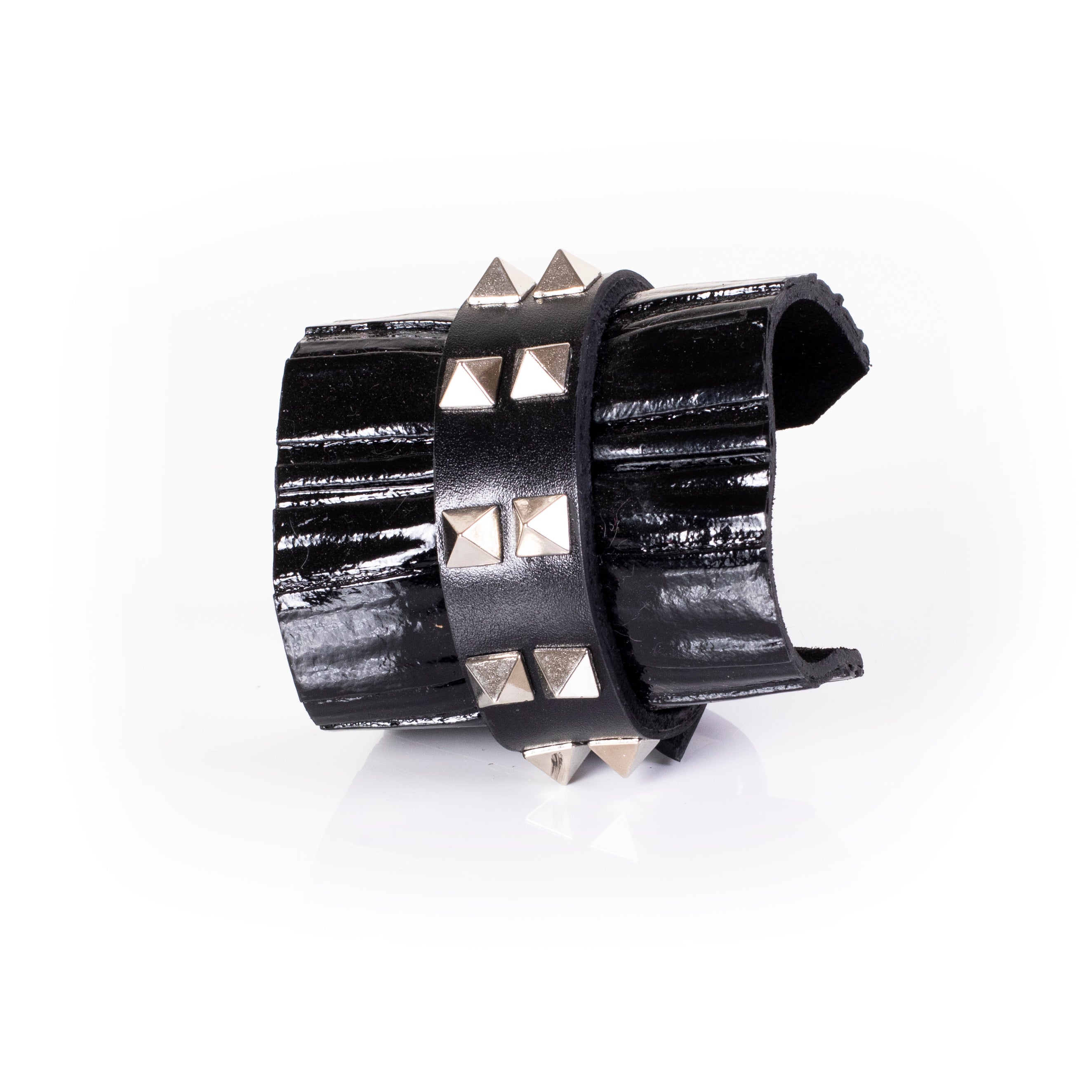 Black patent leather cuff bracelet with central studded leather band and glossy textured surface, wide handcrafted statement bracelet for women by THE DARK