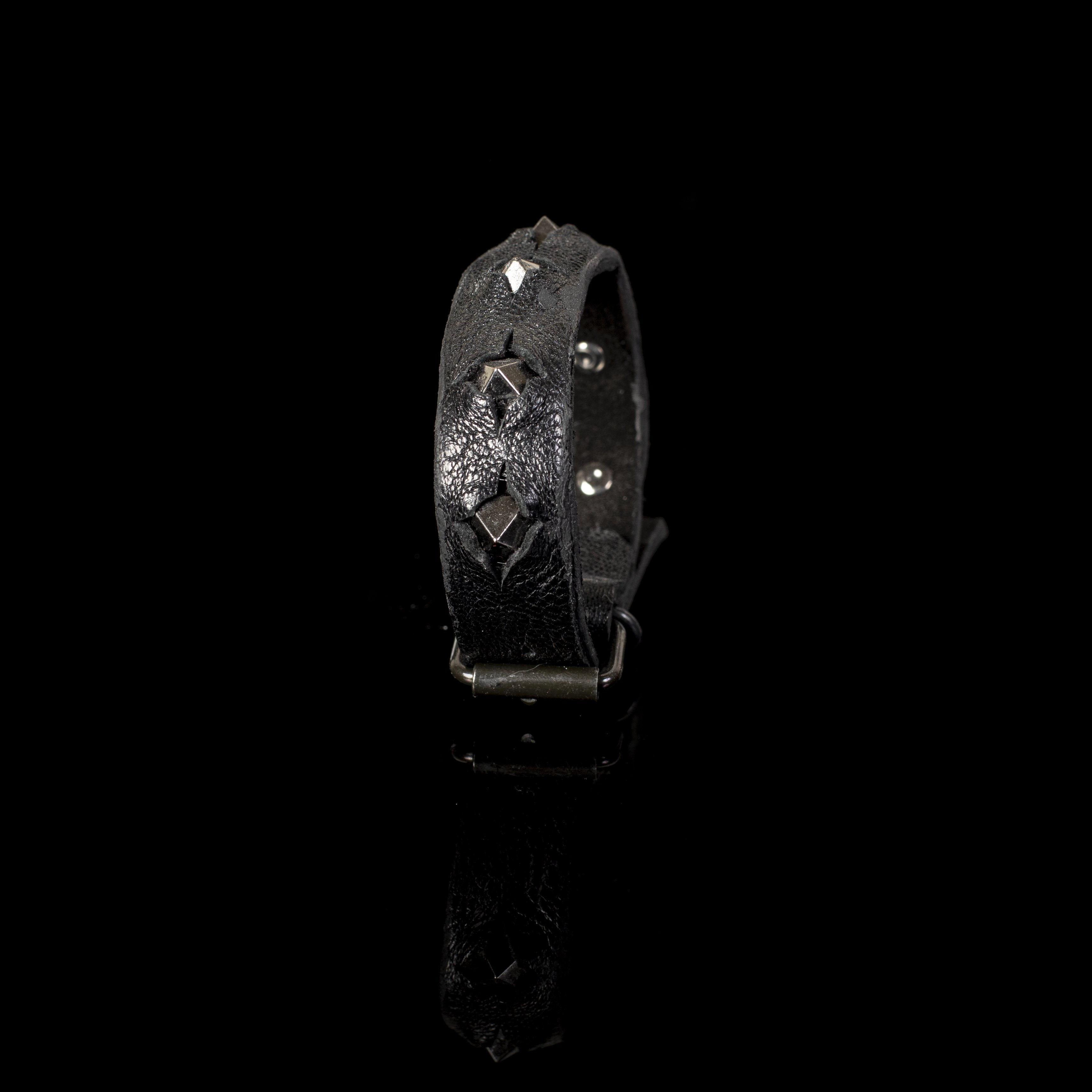 Men's black leather cuff bracelet featuring gunmetal pyramid studs and adjustable snap-button closure on a white background.